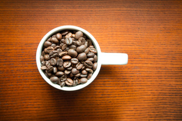 coffee beans in white mug on wooden background