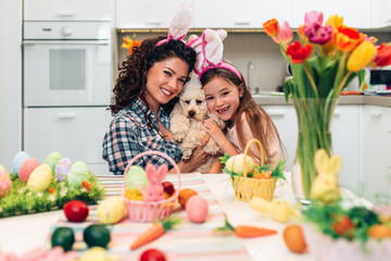 Mother and daughter enjoying with their poodle dog, while preparing for Easter.
