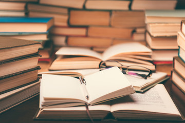 Open book and glasses on wood desk in the library room with narrow depth of field for education background and back to school concept