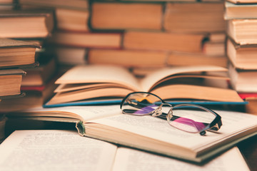Open book and glasses on wood desk in the library room with blurred focus for education background and back to school concept