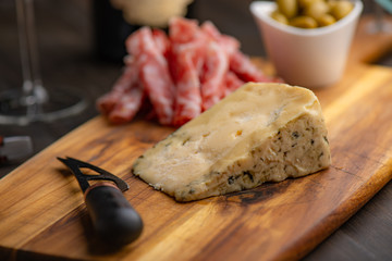Cheese plate with wine in the background on a dark wood table.​