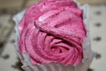 Round big pink marshmallow in paper packaging, close-up on a white background.