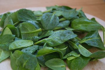 Fresh spinach leaves with water drops on wooden table. Plastic tray, wooden board. Baby spinach leaf - organic and healthy vegetarian food. Healthy lifestyle organic ingredient