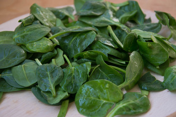 Fresh spinach leaves with water drops on wooden table. Plastic tray, wooden board. Baby spinach leaf - organic and healthy vegetarian food. Healthy lifestyle organic ingredient