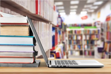 Stack of books with laptop on table