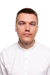 Obraz premium Charming handsome young man in a white shirt is making faces, while standing isolated on a white background