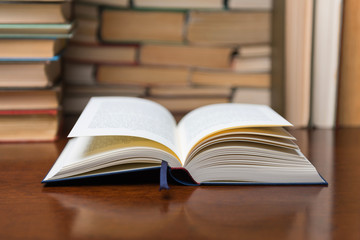 open book on the table, on the background of many books