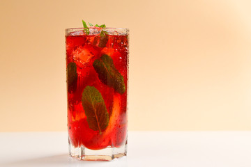 Red fresh drink with ice, grapefruit and mint on an beige background. Space for text or design.