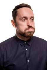 Obraz premium Portrait of a handsome, unshaven man, dressed in a dark blue shirt, standing against a white background. Self confident man.