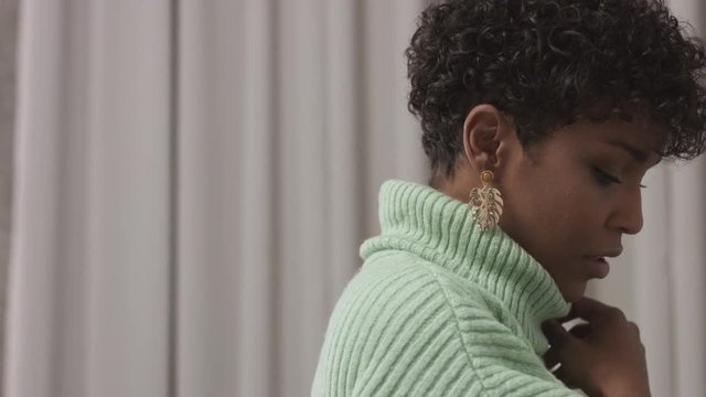 woman in mint sweater in studio with grey curtain background, 90's offise style. CLoseup portrait woman turing to the right and then watching to the camera