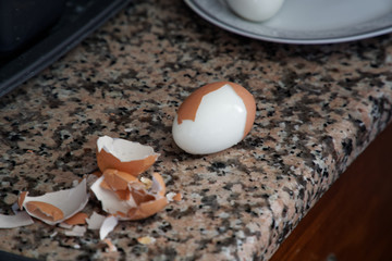 Hard boiled eggs with shell beside on granite board (Selective Focus, Focus on the front of the shell on the first egg).