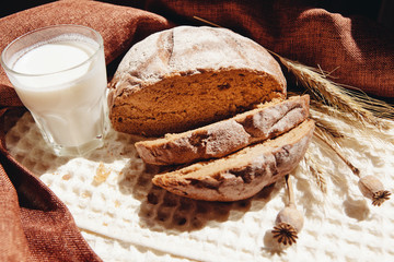 Loaf of bread with milk or yogurt on table