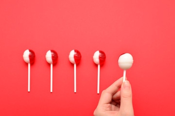 Lollipop in female hand on red background. Space for text or design.