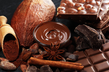 Melting chocolate or melted chocolate with a chocolate swirl and stack, chips and powder on black