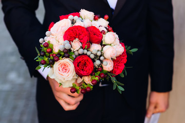  groom in a stylish suit holding a tender wedding bouquet with r