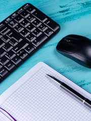 Office table desk. Workspace with blank note book, keyboard, office supplies, on wooden background.
