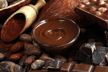 Melting chocolate or melted chocolate with a chocolate swirl and stack, chips and powder on black