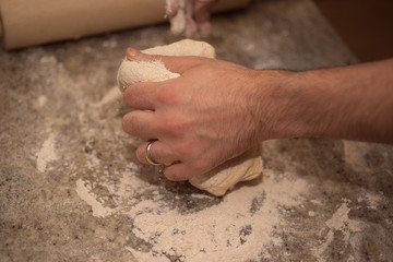 Male hands preparing dough  on table, closeup view.