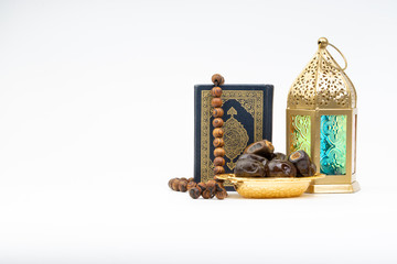 Lantern, Dates, Koran and Rosary on white background with selective focus and crop fragment. Ramadan, Religion and Copy space concept