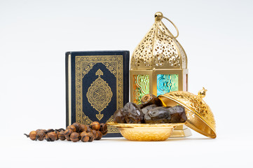 Lantern, Dates, Koran and Rosary on white background with selective focus and crop fragment. Ramadan, Religion and Copy space concept