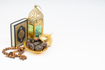 Lantern, Dates, Koran and Rosary on white background with selective focus and crop fragment. Ramadan, Religion and Copy space concept