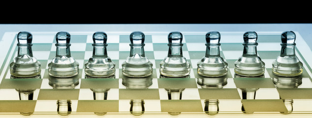 Row of glass chess pawns on a board with blue and orange shade