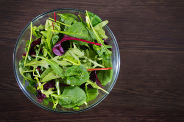 Mixed leaves of green lettuce on a wooden table. A view from above.