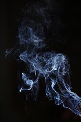 Obraz premium White and blue smoke on a black background. Sharp curls and smoke and out of focus.