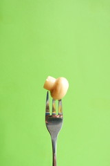 Obraz na płótnie Canvas Marinated mushroom on a fork. Food on green background