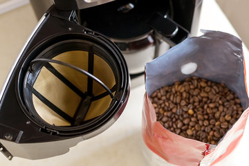 Basket coffee filter, drip-type coffee maker and coffee beans on the kitchen table, top view. Reusable metal mesh coffee filter.