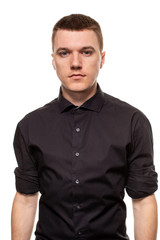 Handsome young man in a black shirt is making faces, while standing isolated on a white background