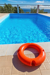 Fototapeta na wymiar Orange life buoy lying at swimming pool