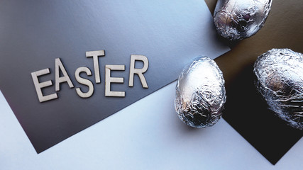 Eggs in foil on silver background. Easter concept banner. With text Easter