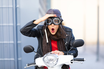 Beautiful young girl in town with white motorbike and black leather jacket