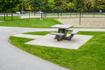 Picnic table and benches on green lawn in a park