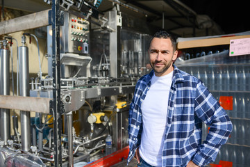young man wine maker working filling wine bottle with automatic bottling machine