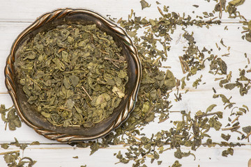 Lot of pieces of dry green tea in old iron bowl flatlay on white wood © PIXbank
