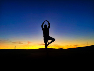 silhouette of woman practicing yoga at sunset