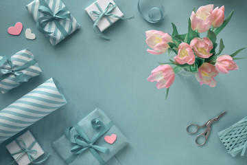 Blue background with pink tulips, stripy wrapping paper and gift boxes
