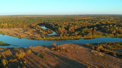 Autumn landscape with a river. Flying over the river at sunset. Boat moving on the river