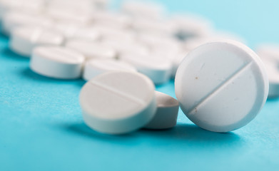 Assorted pharmaceutical medicine pills, tablets and capsules. Blue background.