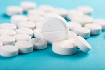 Assorted pharmaceutical medicine pills, tablets and capsules. Blue background.