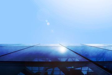 the facade of the glass building and the bottom view of the sky with a sun flare