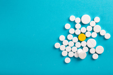 Assorted pharmaceutical medicine pills, tablets and capsules. Blue background.