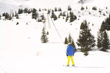 Fotobehang Man on a ski resort taking the pole to rich to the top of the mountain to ski  © raeva