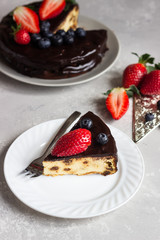 Cheesecake with raisin decorated with chocolate glaze and fresh strawberries and blueberries.