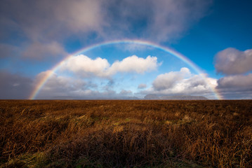 white clouds and rainbow photo on horizon