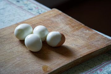 Fototapeta na wymiar Hard boiled eggs with shell beside on wooden board