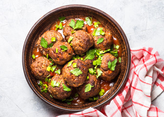 Meatballs in tomato sauce on light stone table top view.