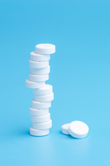 White pills or tablets stacked on each other in different positions on blue background